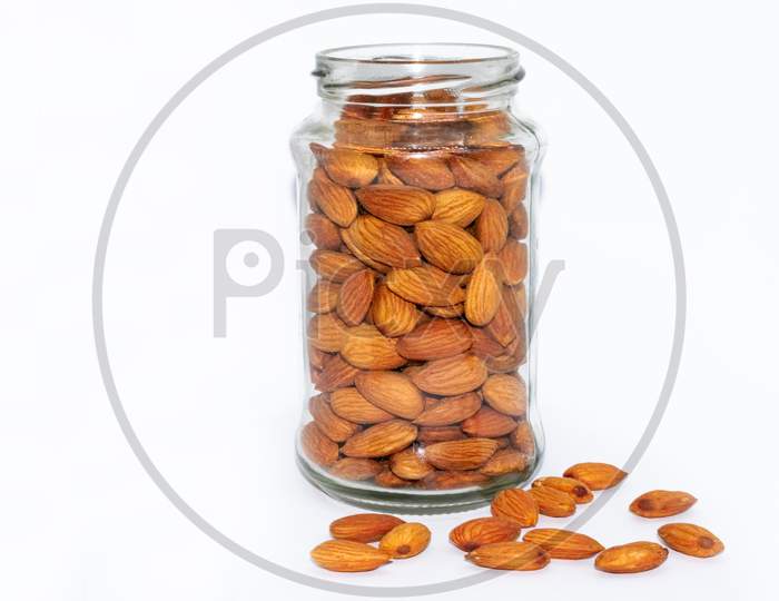 Fresh almond nuts into glass jar isolated on white background
