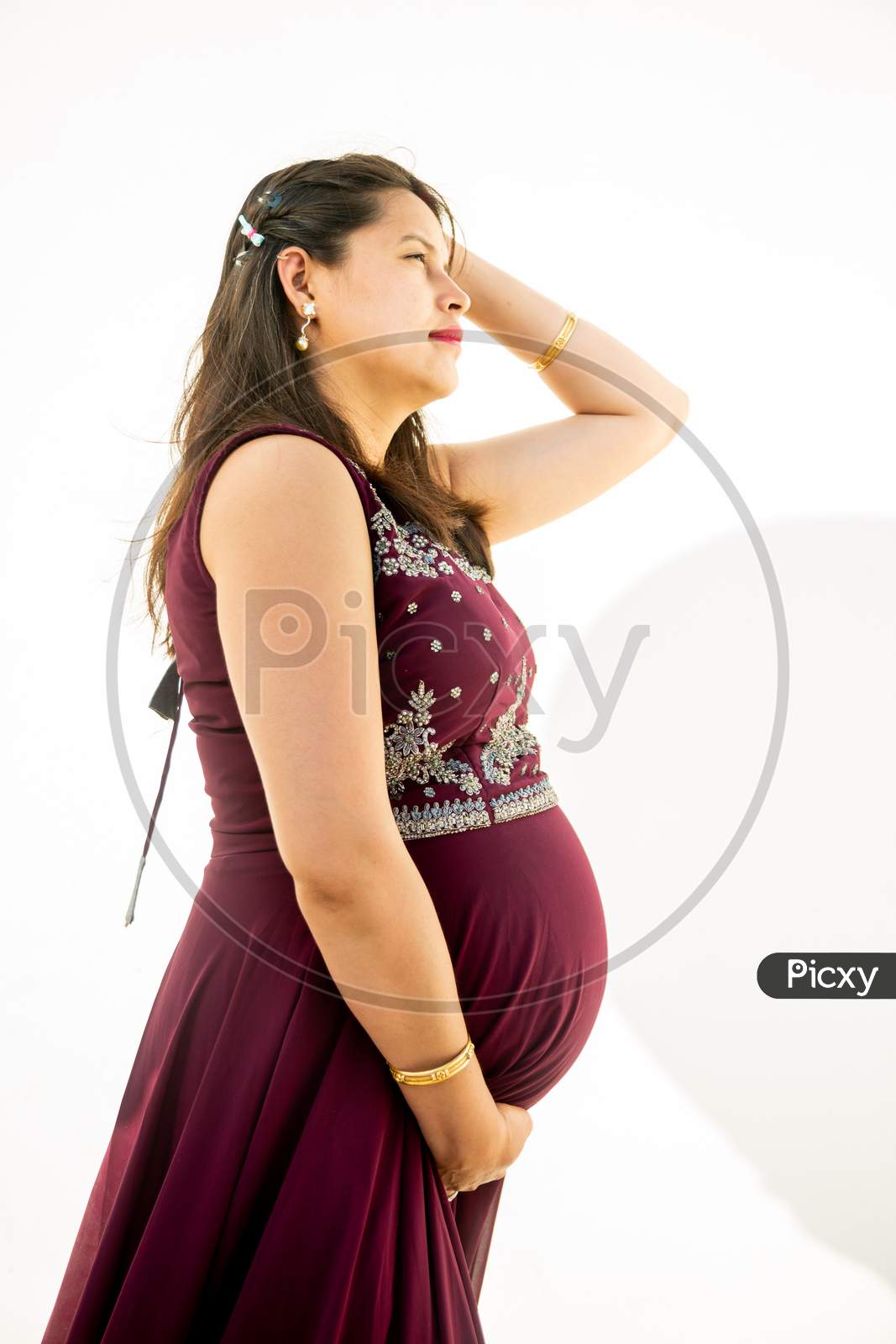 Image Of Young Asian Indian Pregnant Woman Looking At Belly Standing Against White Background 