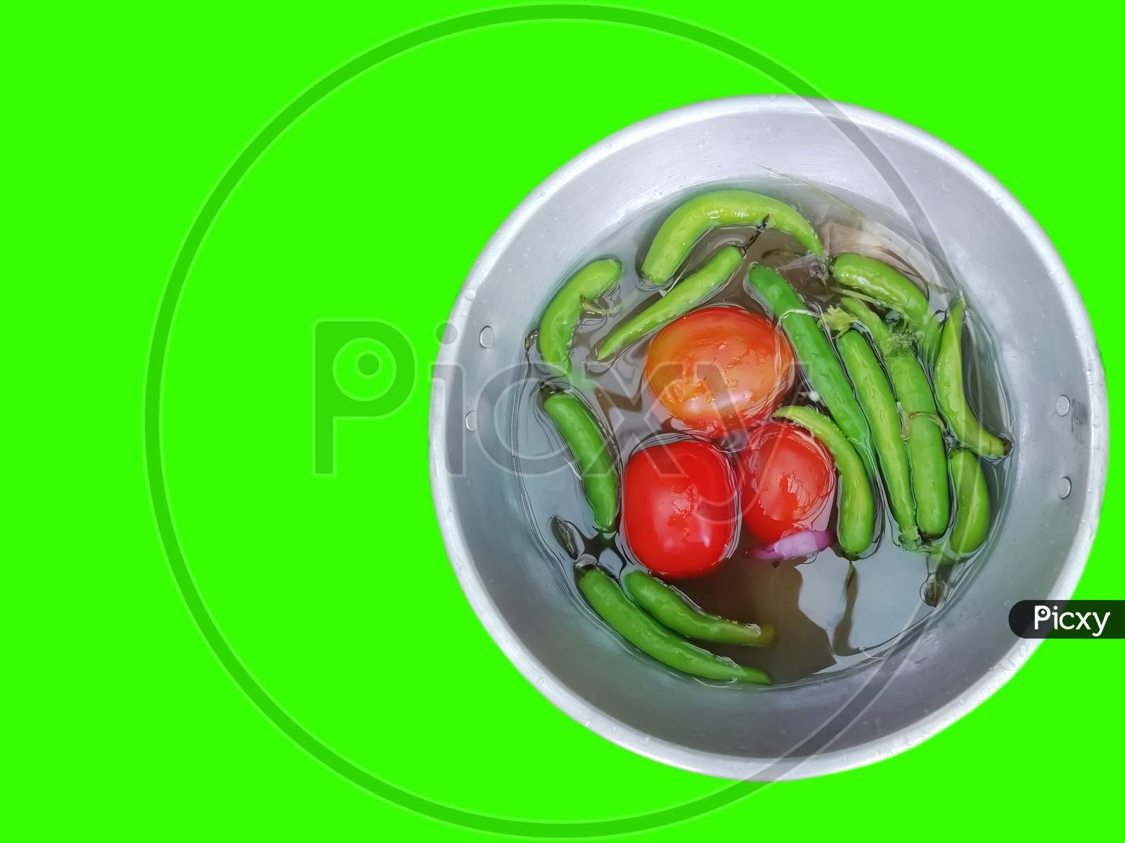 Closeup Of Tomatoes And Green Chili Peppers In A Bowl Isolated On Green Background