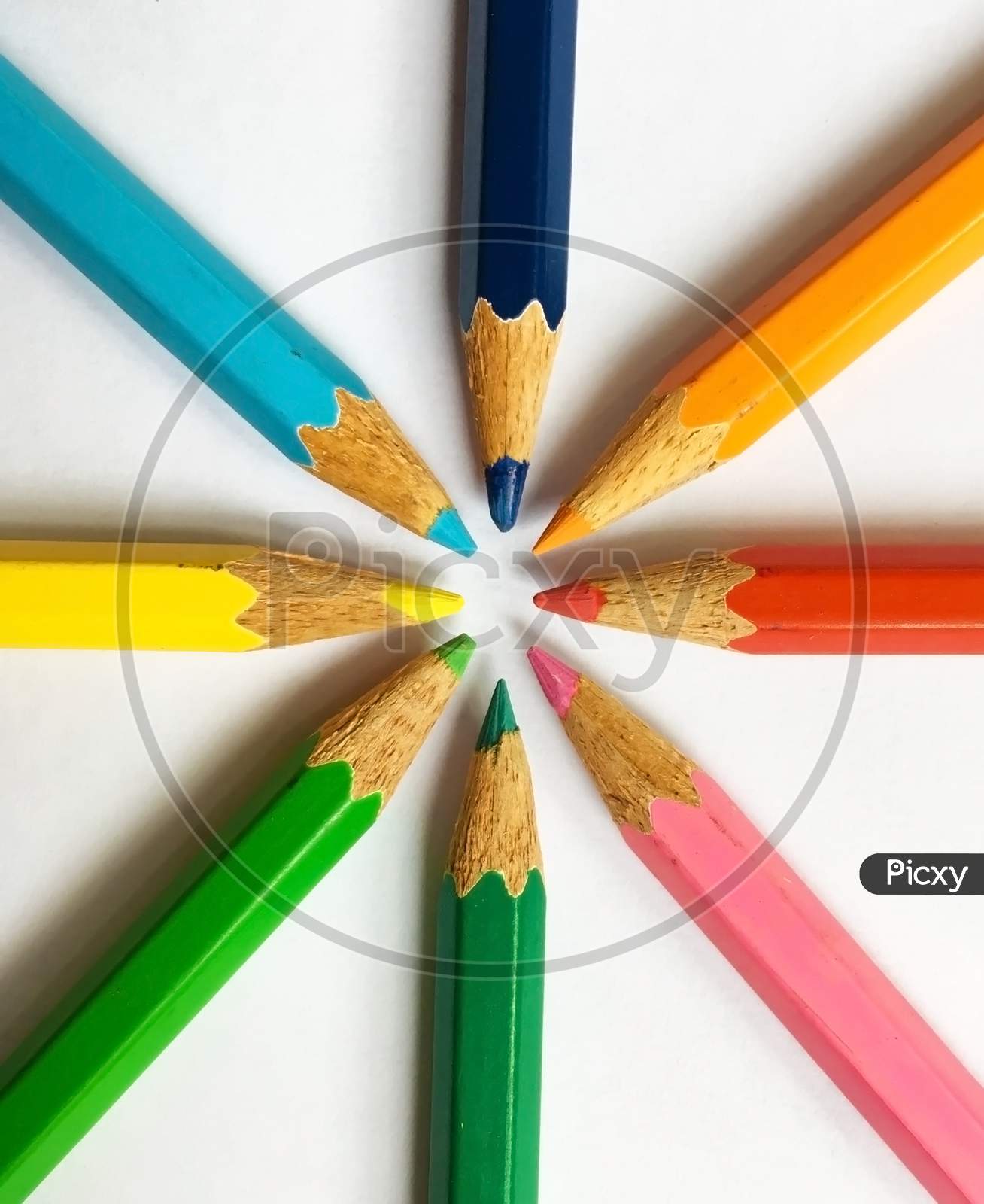 Colored wooden pencils on white background in a circular manner