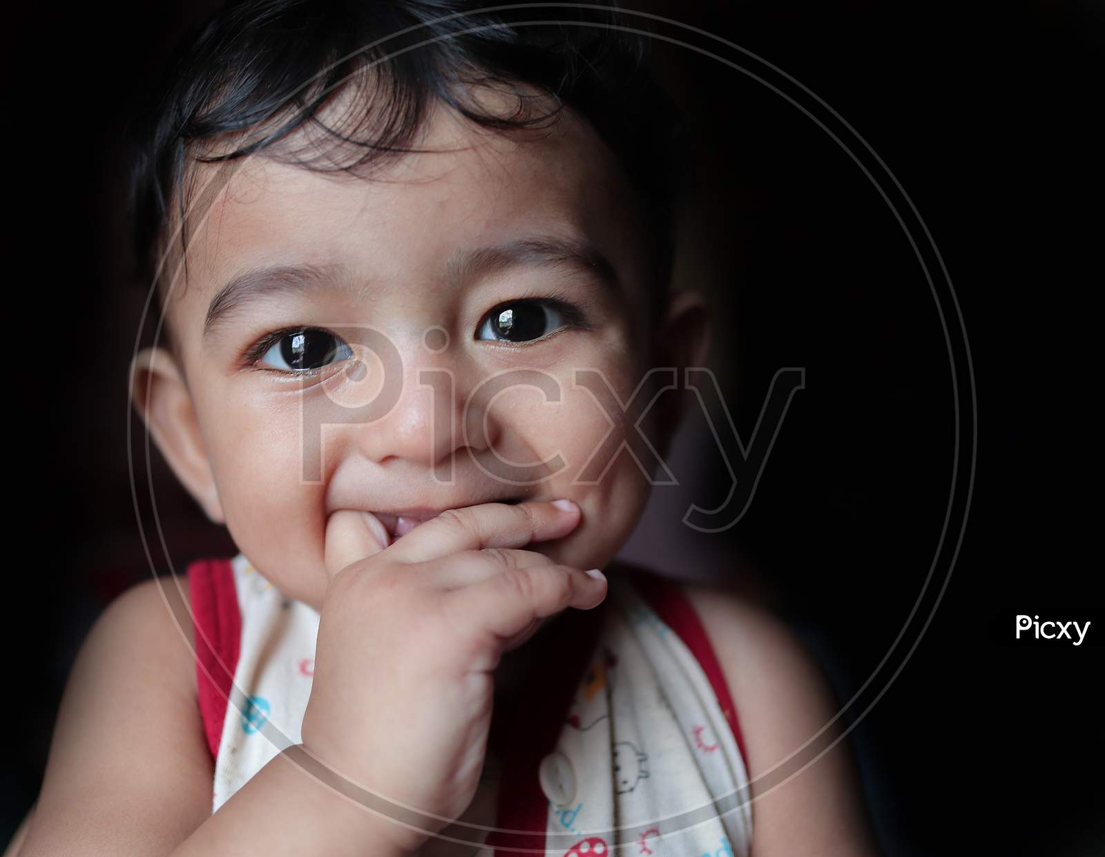 A Head Shot Portrait Of An Adorable Indian Baby Looking At The Camera With Selective Focus On Eyes With Black Background