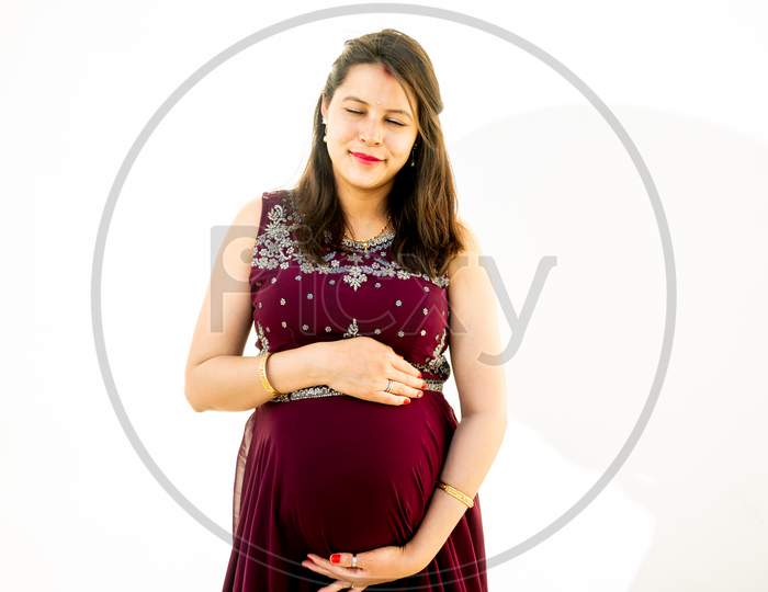 Young Pregnant Woman Looking At Belly Standing Against White Background Outdoor Studio Shot, Happy Female Expecting Baby, Motherhood And Pregnancy Concept, Copy Space.