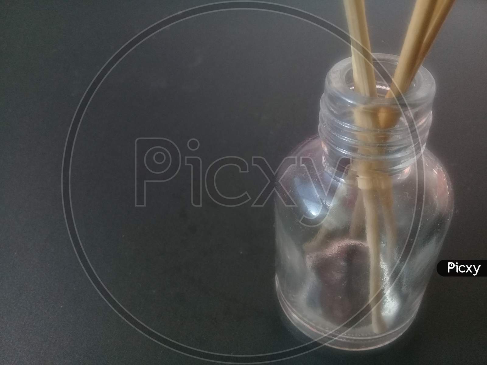 Close-Up Of Incense Sticks In Glass Container Against Gray Background