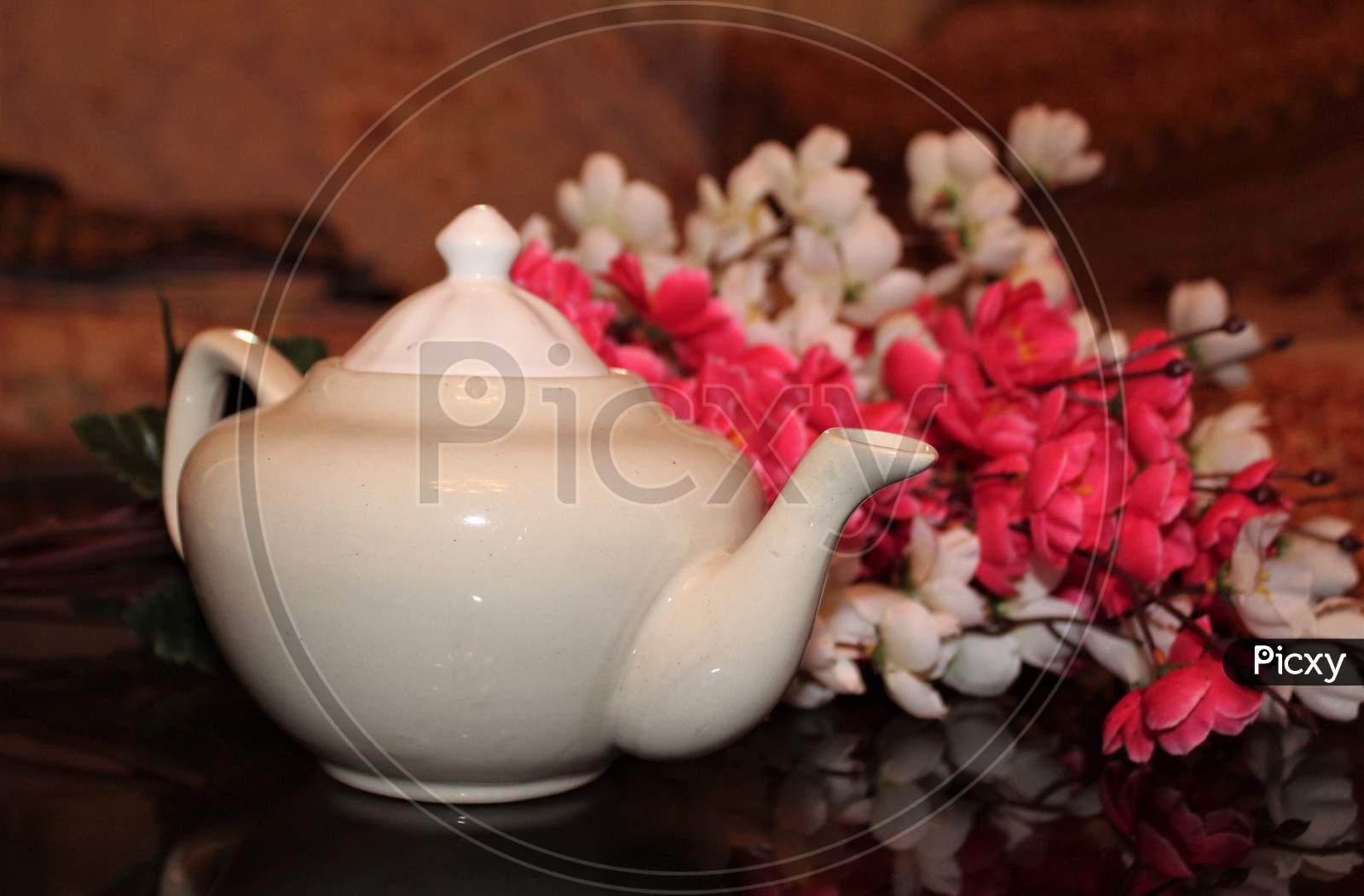 This picture shows a white tea pot with pink flowers