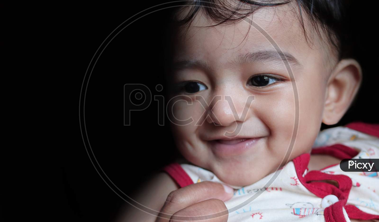 A Head Shot Portrait Of An Adorable Indian Baby Looking At Downwards And Left With Selective Focus On Front Eye With Copy Space In Black Background