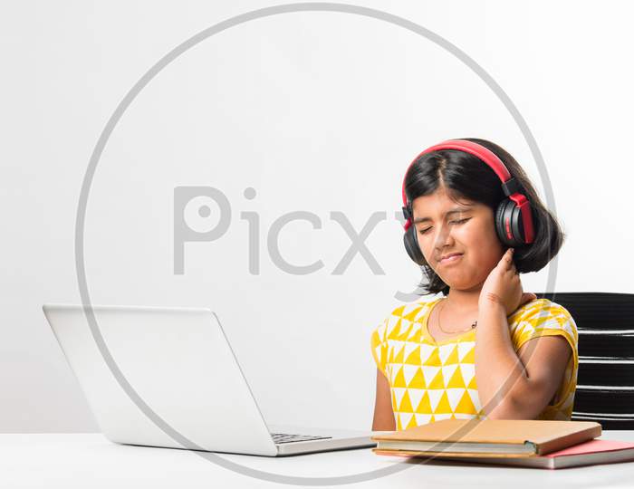 Indian Asian Small School Girl Learning Online Or Attending School Using Tablet Or Laptop Computer