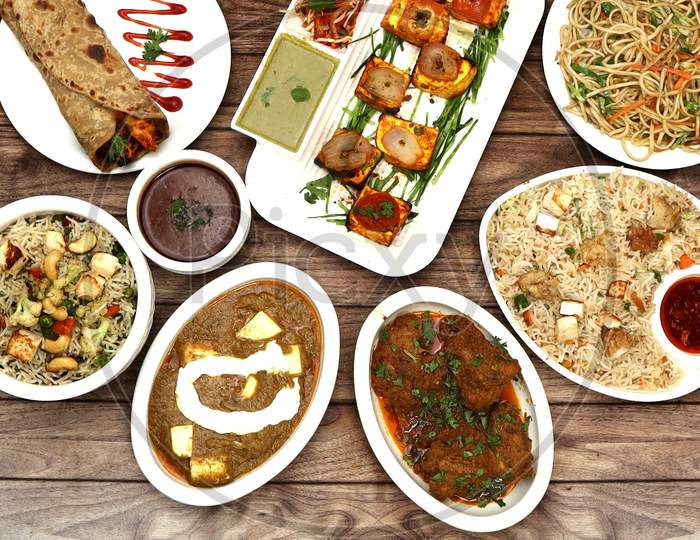 Assorted Indian Food On Wooden Background. Paneer Tikka, Paneer Pulao, Paneer Fried Rice, Chicken Gravy, Chicken Gravy And Veg Noodlesdishes And Appetizers Of Indian Cuisine