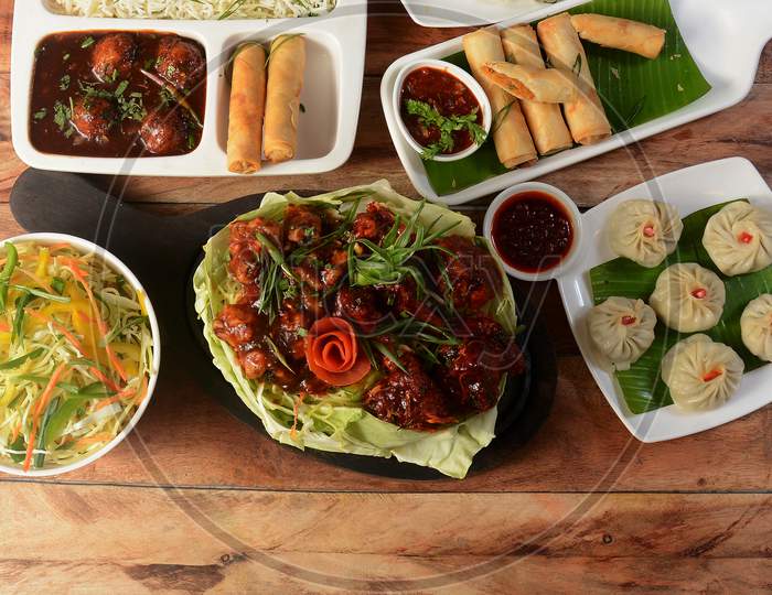 Assorted Indian Food On Wooden Background. Gobi Manchurian, Spring Roll, Veg Ball Manchurian, Noodles And Fried Rice.Dishes And Appetizers Of Indian Cuisine