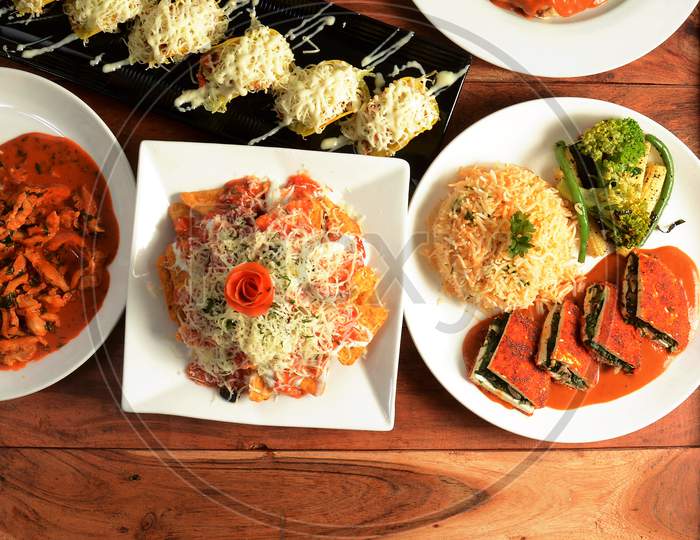 Assorted Indian Food On Wooden Background. Cottage Cheese Steak With Herb Rice, Cheese Nachos.. Dishes And Appetizers Of Indian Cuisine