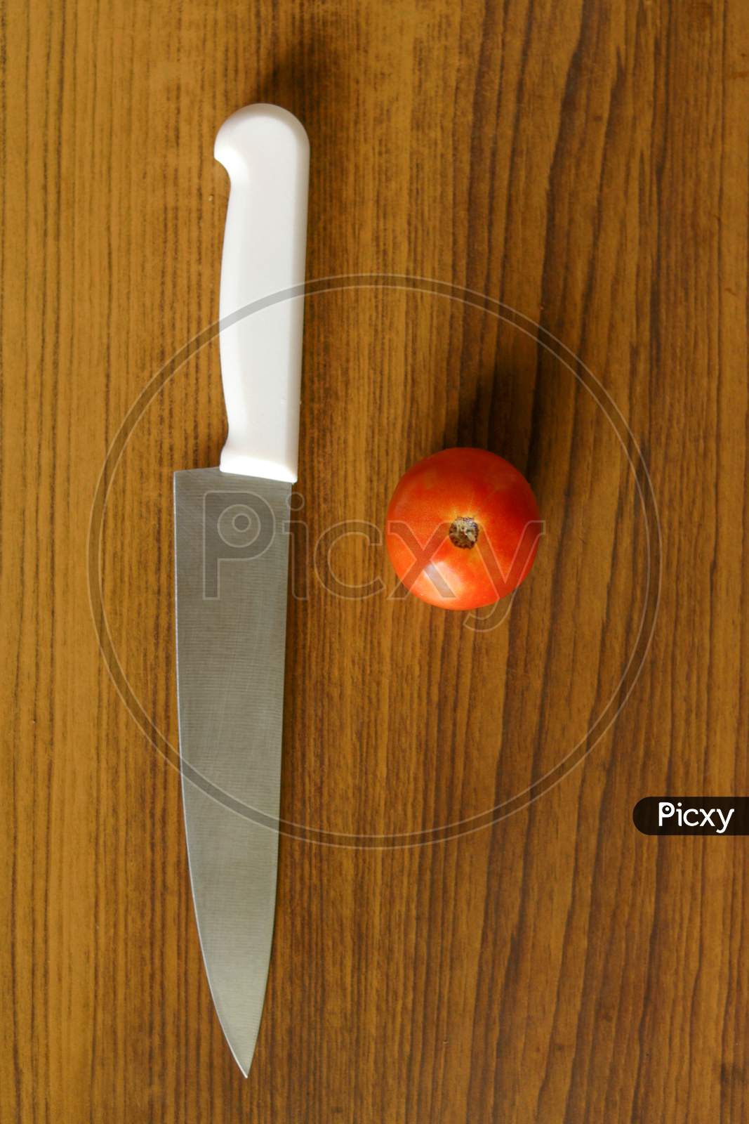 close up shot of a knife and an organic tomato