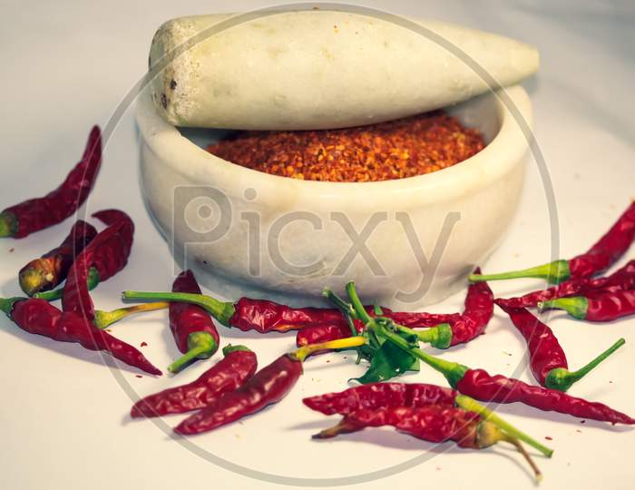 closeup of hot chili peppers and its powder in motor pestle