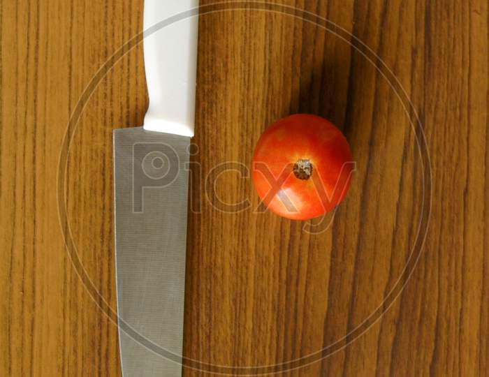close up shot of a knife and an organic tomato