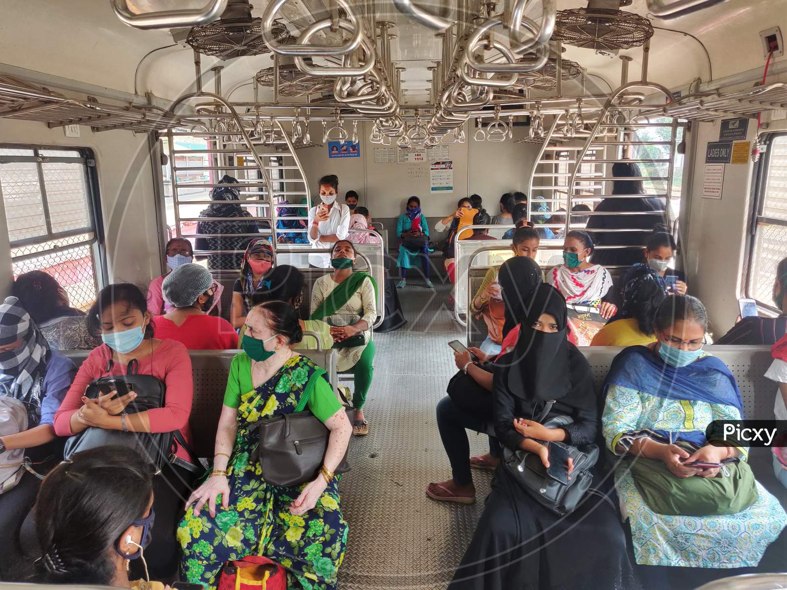 Women wearing protective face masks commute in a suburban train after authorities resumed the train services for women passengers during non-peak hours, amidst the coronavirus disease (COVID-19) outbreak, in Mumbai, India, 2020.
