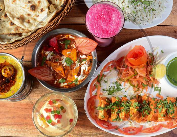 Assorted Indian Food On Wooden Background. Paneer Tikka, Dal Tadka,Jeera Rice,Roti.. Dishes And Appetizers Of Indian Cuisine