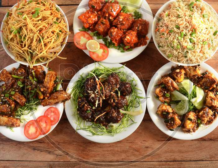 Assorted Indian Food On Wooden Background. Veg Ball Manchurian,Chilli Paneer,Paneer Manchurian,Hakka Noodles, Vegfried Rice And Baby Corn Manchurian.. Dishes And Appetizers Of Indian Cuisine