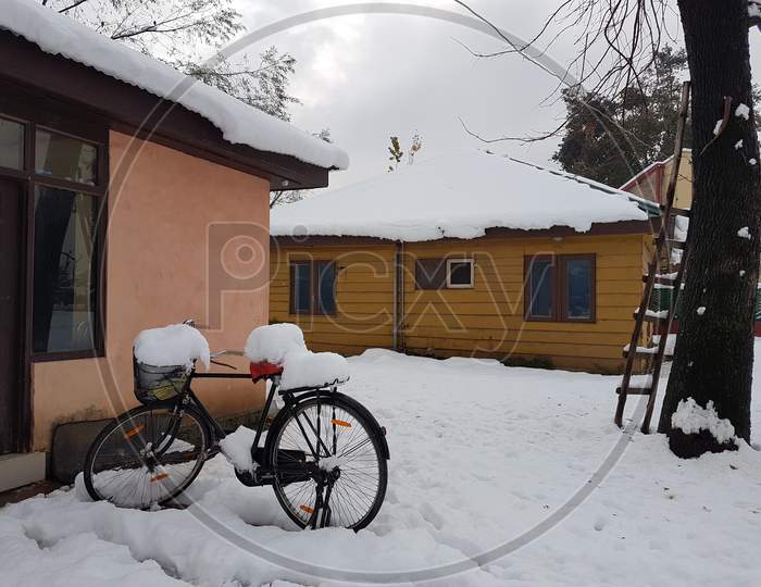 Snowfall photo with bicycle having snow