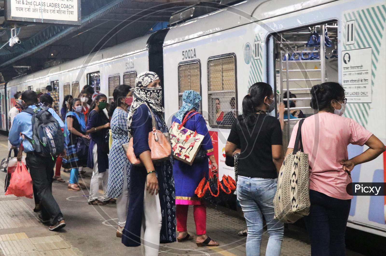 Women wearing protective face masks board a local train after authorities resumed the train services for women passengers during non-peak hours, amidst the coronavirus disease (COVID-19) outbreak, in Mumbai, India, October, 2020.