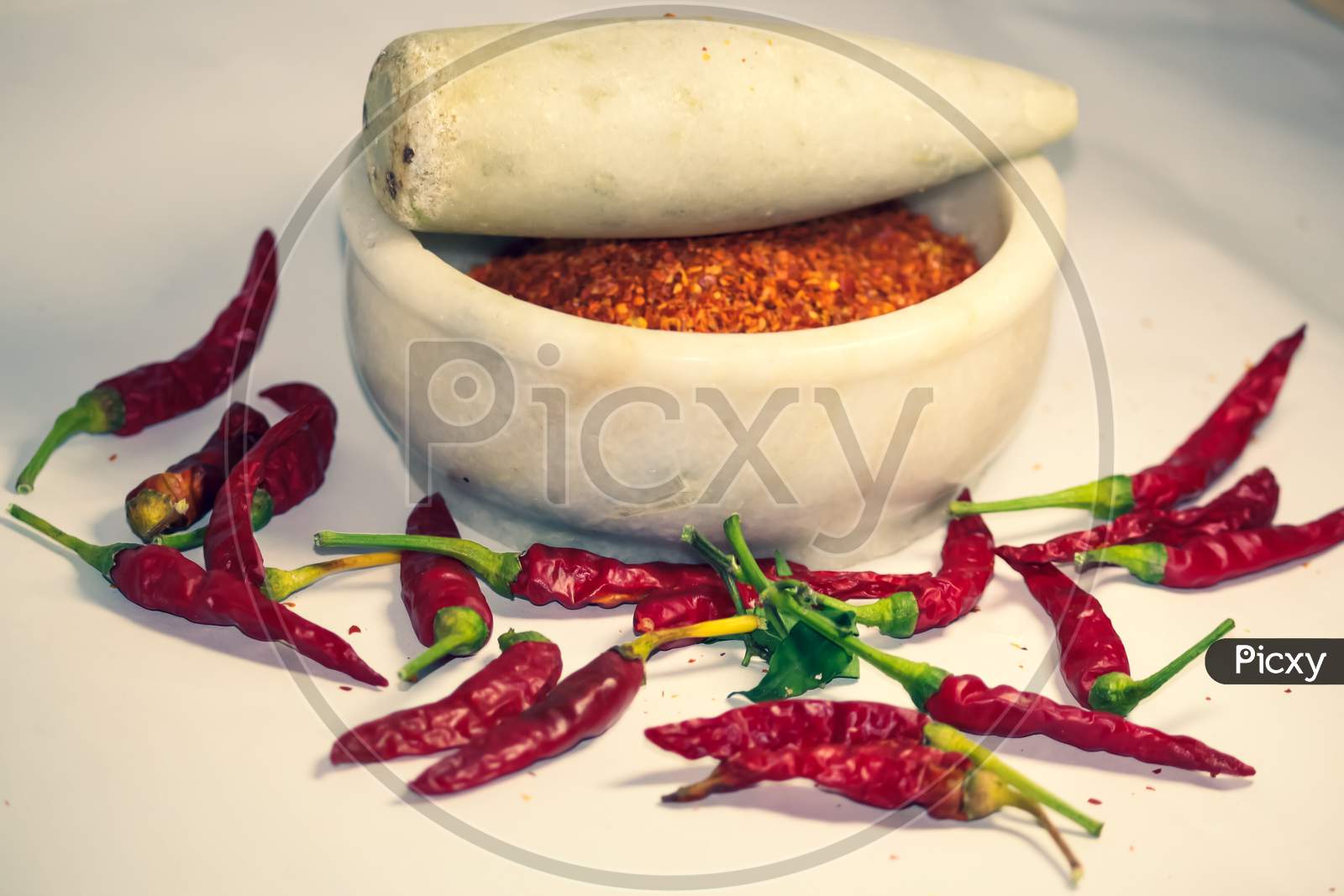 closeup of hot chili peppers and its powder in motor pestle