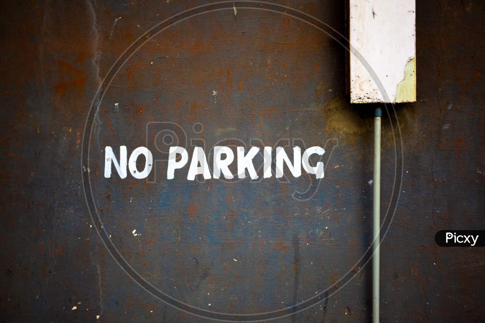 No Parking Text In White Paint On Weathered Wall
