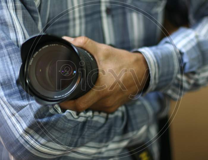 A man holding a camera lens in his hand