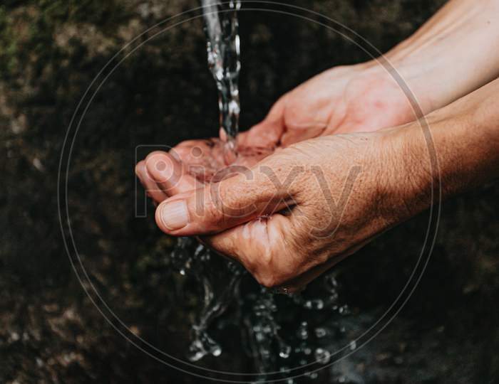 Close Up Of Two Old Hands Taking Water To Drink From A Natural Font In The Forest