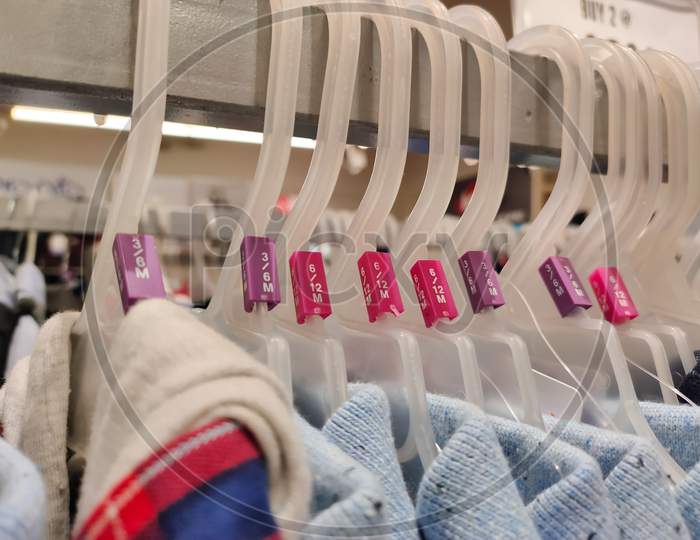 Cloths T-Shirts Hanging From Hanger In A Row In A Shopping Mall Or Shop.