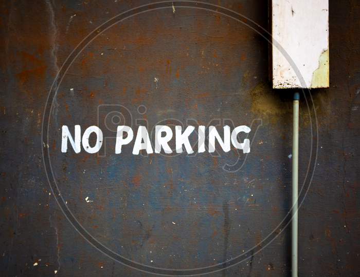 No Parking Text In White Paint On Weathered Wall