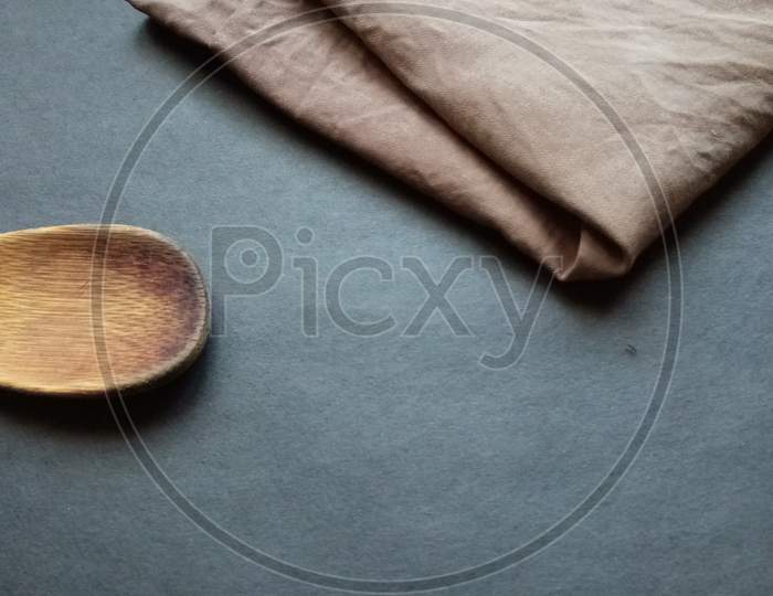 Brown cloth and wooden spoon in black background
