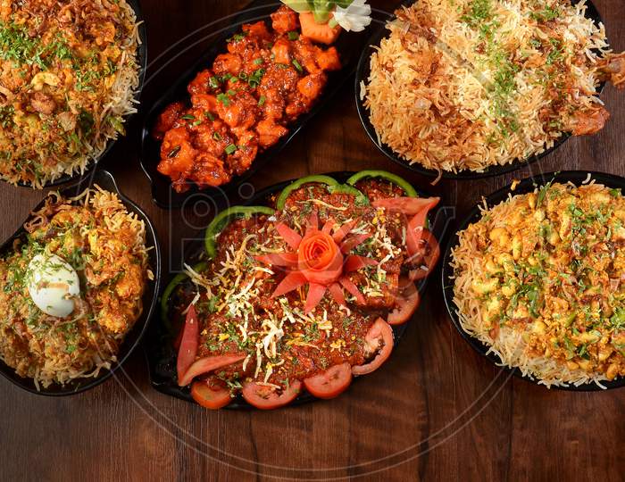Assorted Indian Foods Mughal Chicken Biryani,Chicken Manchurian,Kaju Biryani,Chicken Dum Biryani And Egg Biryani On Wooden Background. Dishes And Appetizers Of Indian Cuisine