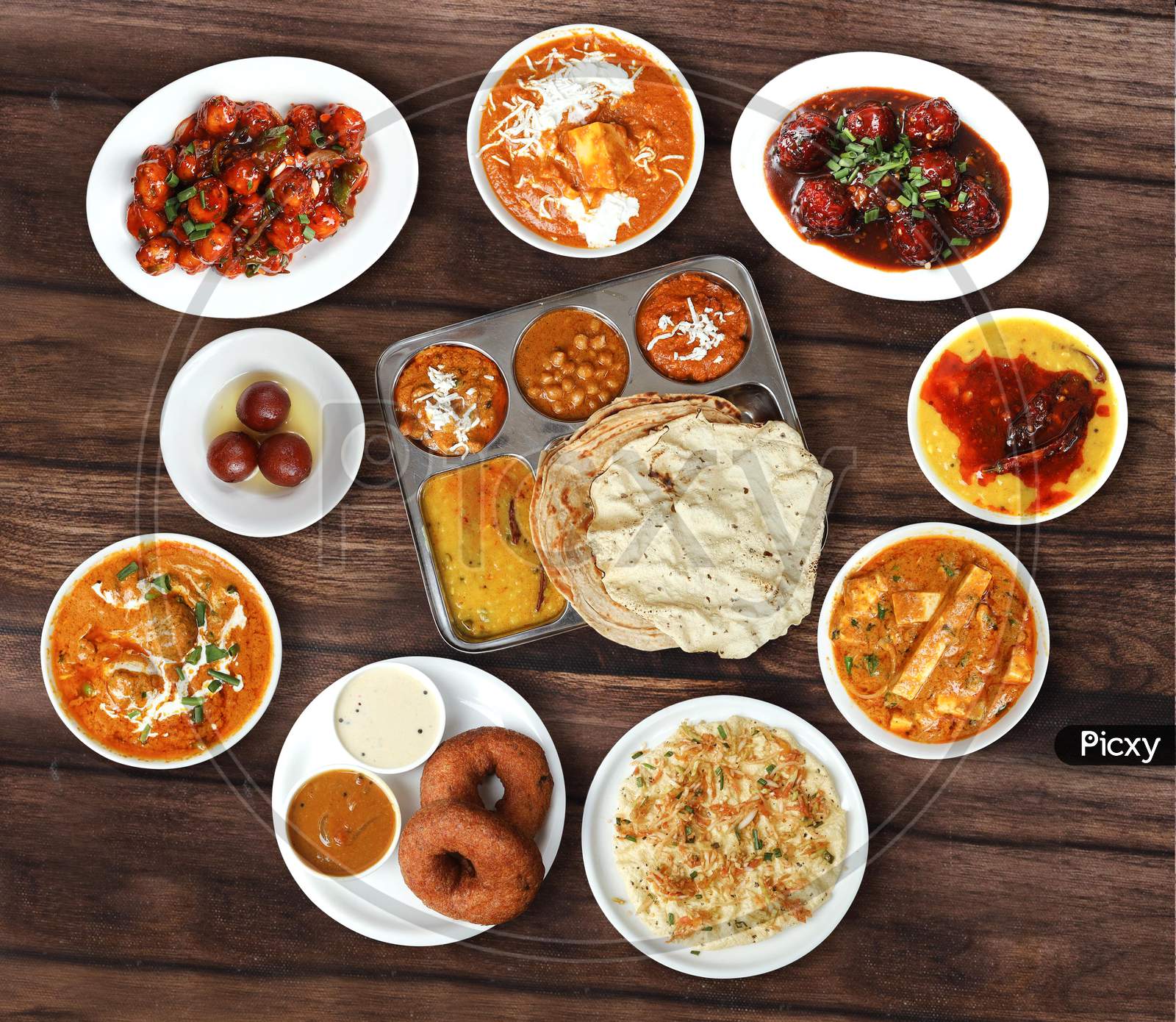 Assorted north indian foods Veg thali,roti,malai kofta,paneer butter masala,veg manchurian and biryani on wooden background. Dishes and appetizers of indian cuisine
