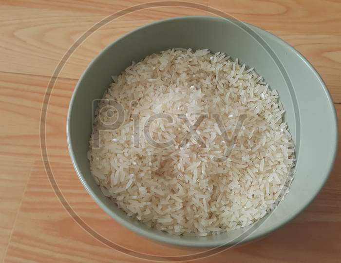 Top Closeup View Of Heap Of Rice In A Ceramic Bowl Placed Over Wooden Floor