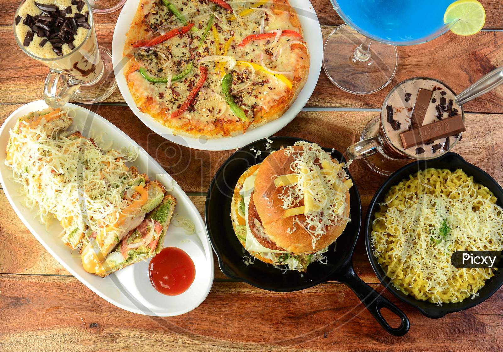 Assorted Foods Cheese Grilled Sandwich,Paneer Cheese Burger,Cheese Maggie And Capsicum Pizza On Wooden Background. Dishes And Appetizers Of Indian Cuisine