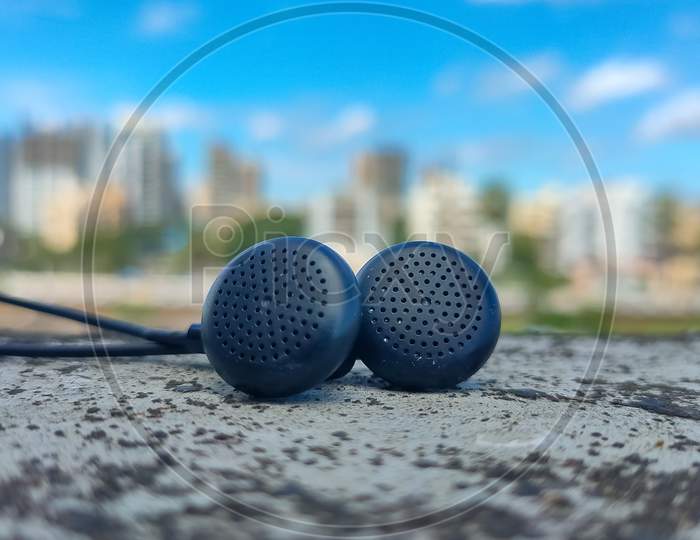 Earphones with blurred background of buildings and Blue cloudy sky.