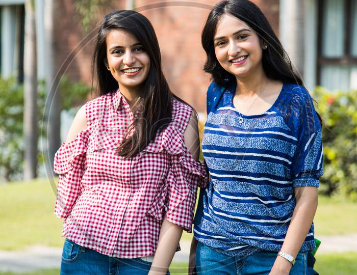 Indian Asian Two Girl Friends Standing, Looking At Camera Against Campus Background