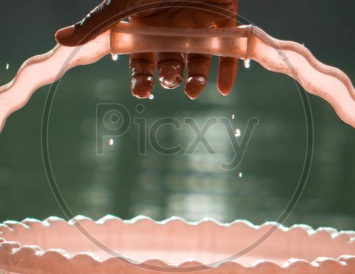 water dripping from wet hand, bucket, pond in background