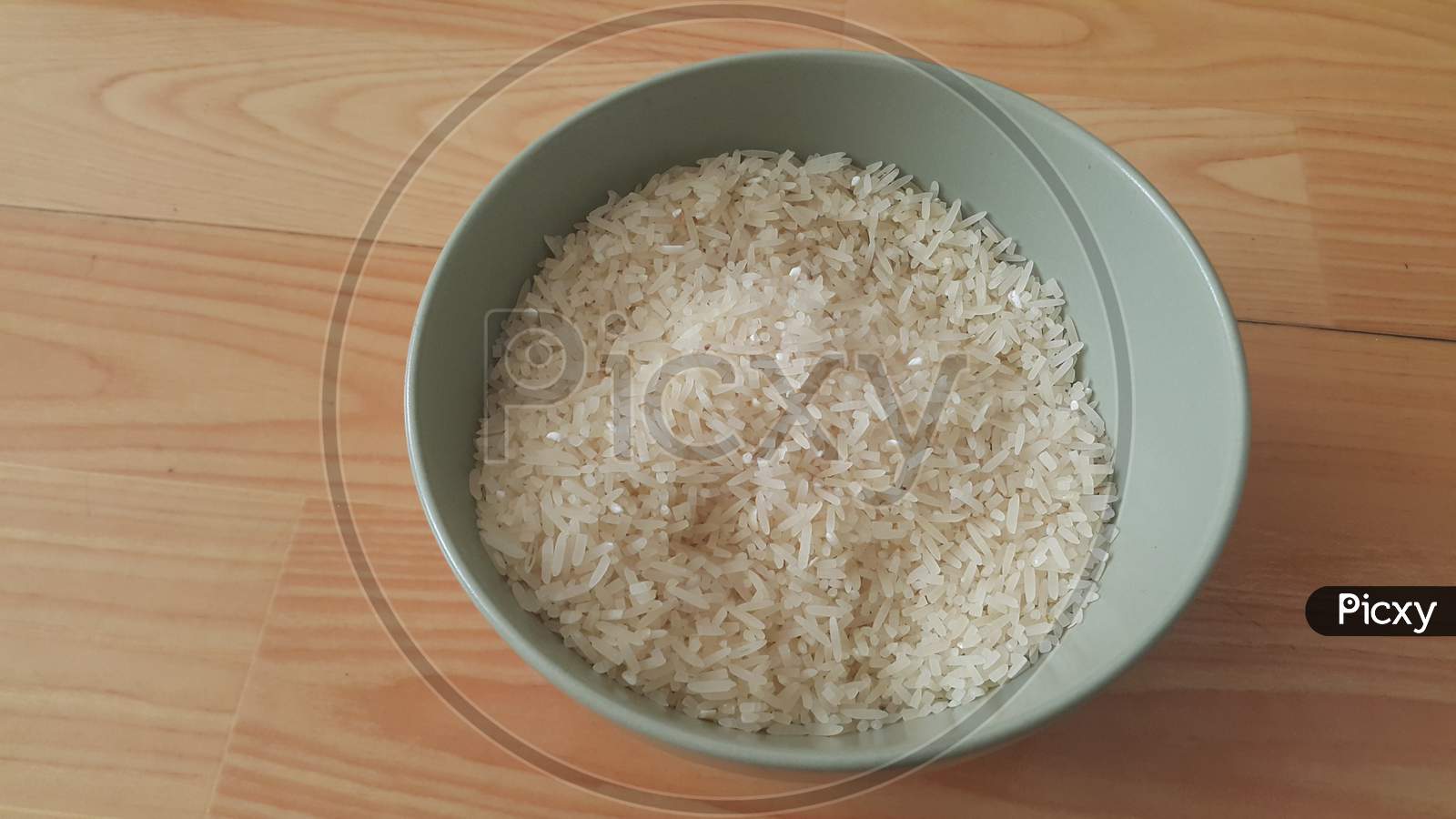 Top Closeup View Of Heap Of Rice In A Ceramic Bowl Placed Over Wooden Floor