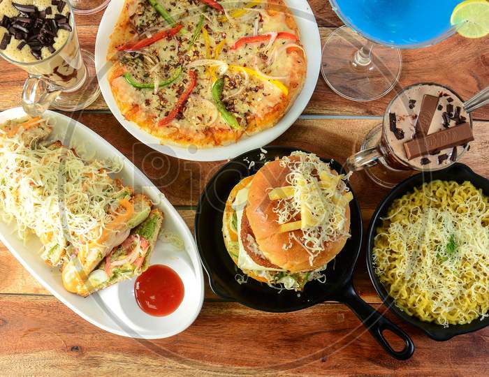 Assorted Foods Cheese Grilled Sandwich,Paneer Cheese Burger,Cheese Maggie And Capsicum Pizza On Wooden Background. Dishes And Appetizers Of Indian Cuisine