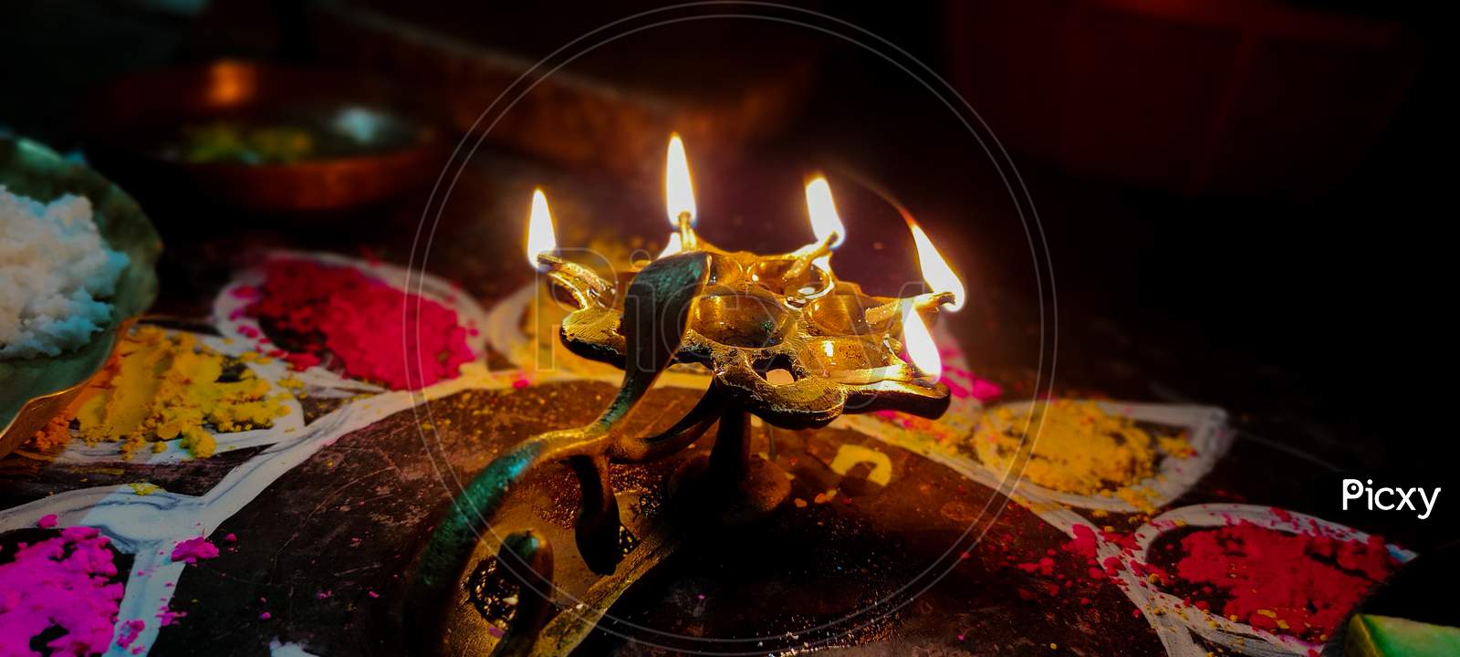 A Glowing Multi Flame Lamp Commonly Known As Panchapradip. A Holy Thing Used As An Offering To God For Worship. Surrounded By Colourful Rangoli.