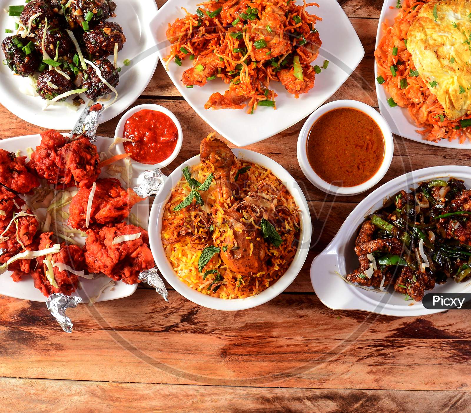 Assorted Indian Foods Chicken Biryani,Chicken Lollipop,Pepper Chicken And Pepper Gobi On Wooden Background. Dishes And Appetizers Of Indian Cuisine