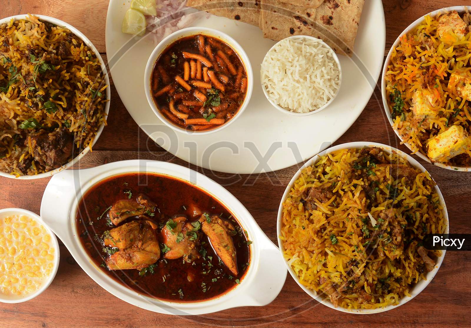 Assorted Indian Foods Chicken Biryani,Mutton Biryani,Paneer Biryani And Chicken Gravy On Wooden Background. Dishes And Appetizers Of Indian Cuisine