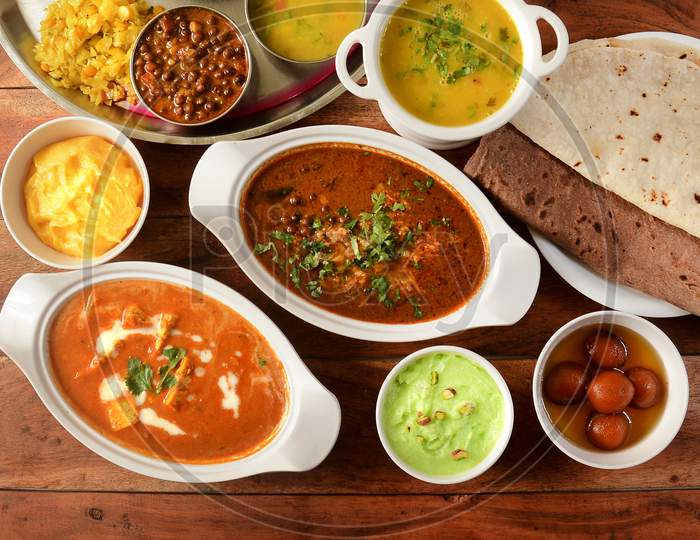 Assorted Indian Foods Paneer Butter Masala,Channa Masala,Roti And Veg Thali On Wooden Background. Dishes And Appetizers Of Indian Cuisine