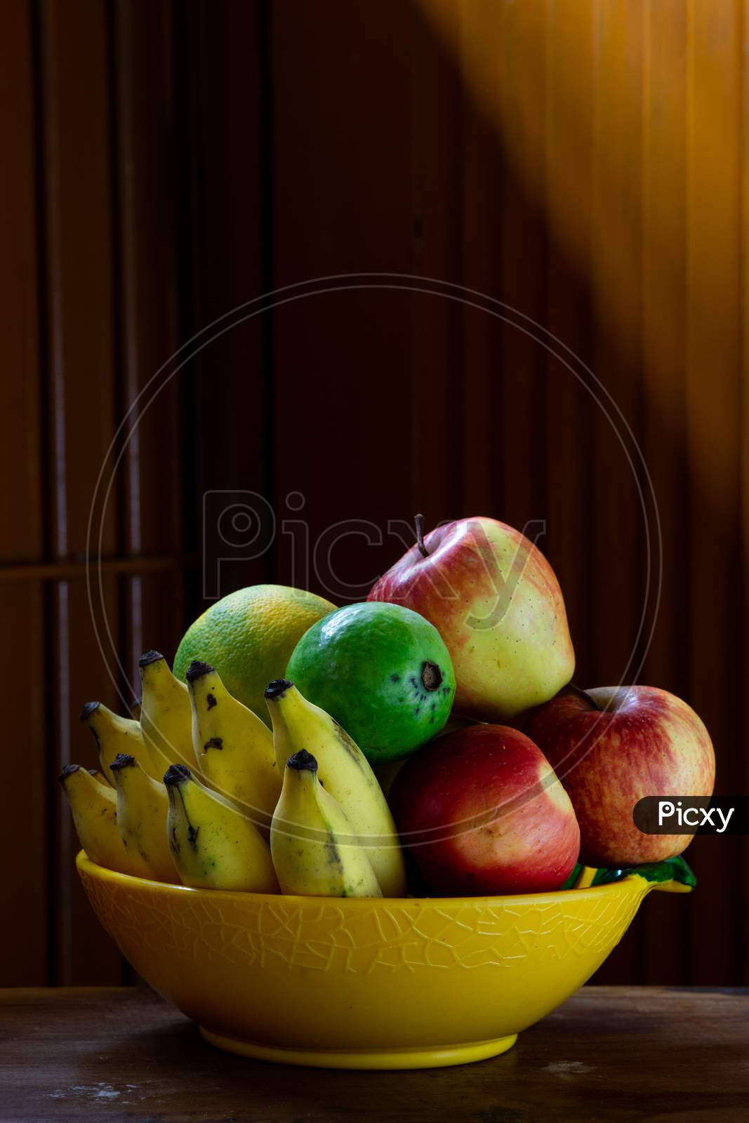 A Bowl Of Fruits With A Wooden Background
