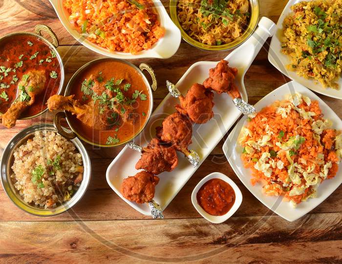 Assorted Indian Foods Sabudana Kichidi,Chicken Lollipop,Chicken Masala And Schezwan Fried Rice On Wooden Background. Dishes And Appetizers Of Indian Cuisine