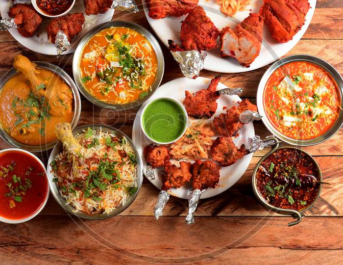 Assorted Indian Foods Chicken Biryani,Chicken Korma,Chicken Lollipop, Paneer Butter Masala And Tandoori Chicken On Wooden Background. Dishes And Appetizers Of Indian Cuisine