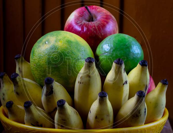 A Bowl Of Fruits With A Wooden Background