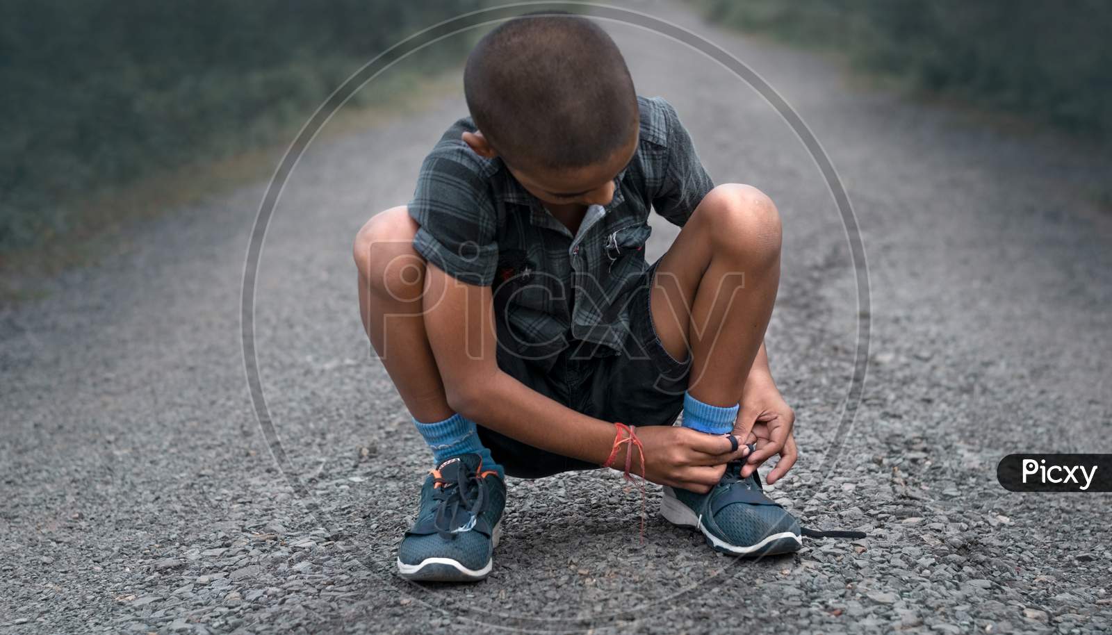 Selective Focus In Child Is Shoe Lacing In Middle Of The Road .