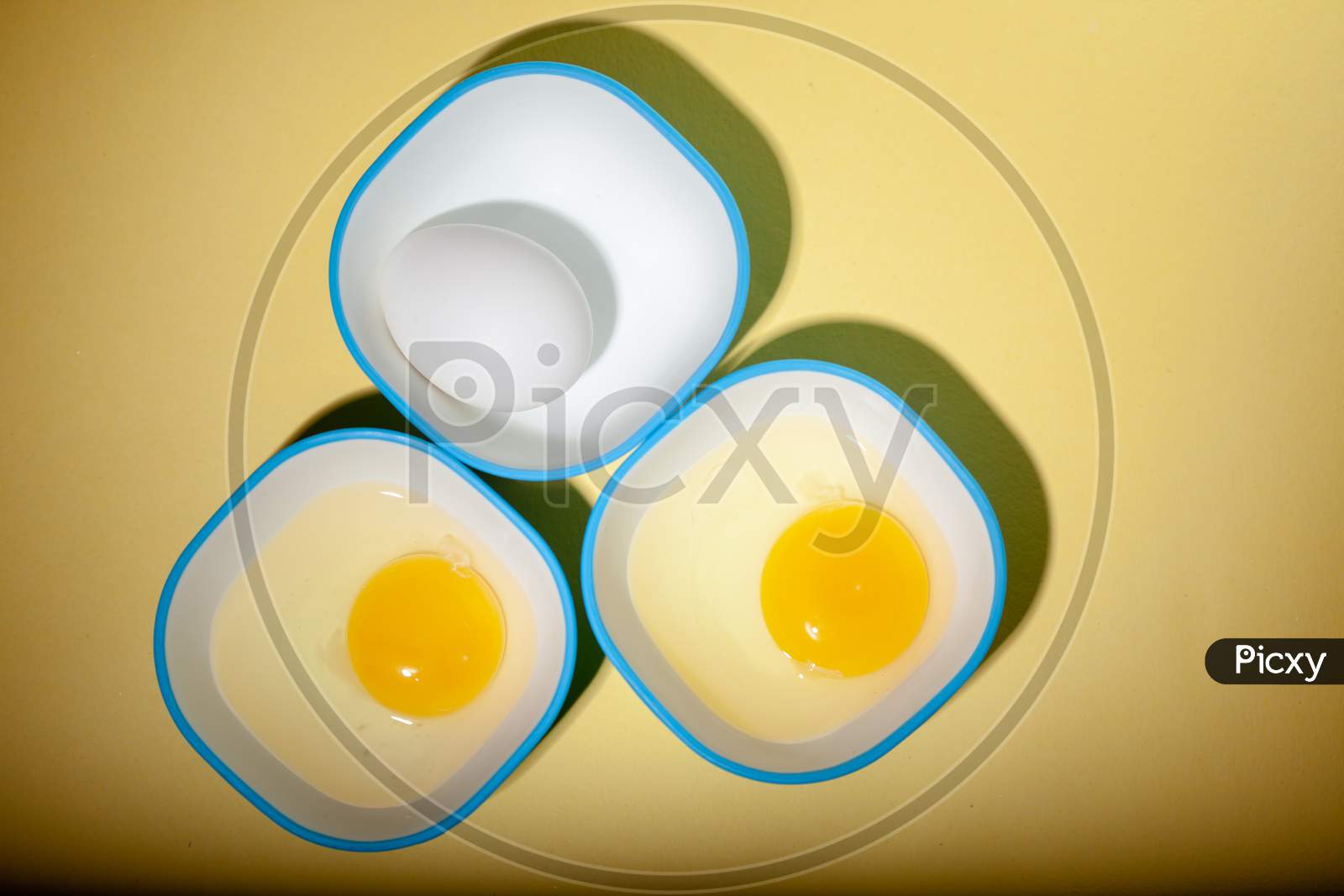 Raw Egg & Yellow Yolk In Three Bowls