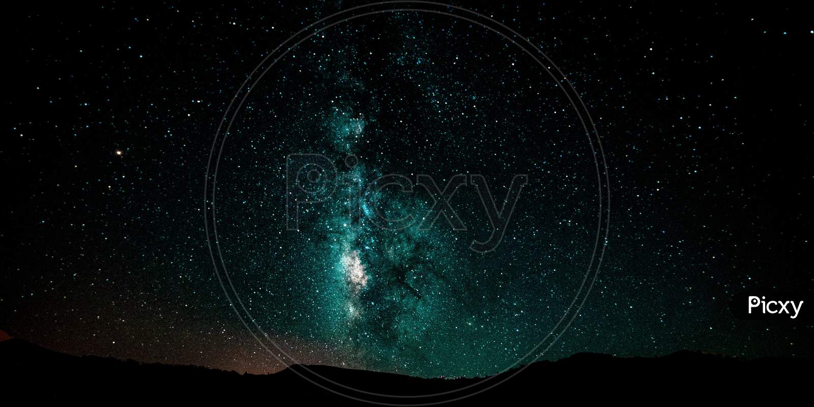 Night landscape with colorful Milky Way and GREEN light at mountains. Starry sky with hills at summer. Beautiful Universe. Space background.