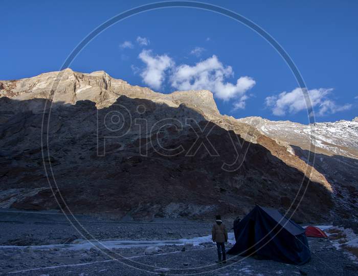 Tenting Ground With Tents In Front Of High Altitude Peaks And Its Shadow In A Cold Sunny Day In The Himalaya In Ladakh