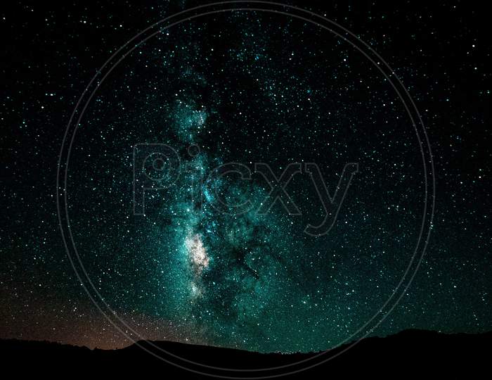 Night landscape with colorful Milky Way and GREEN light at mountains. Starry sky with hills at summer. Beautiful Universe. Space background.